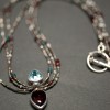 Blue topaz and garnet pendant on a triple strand of vintage French micro metal beads, tiny pearls, garnets and blue apetite.  $325